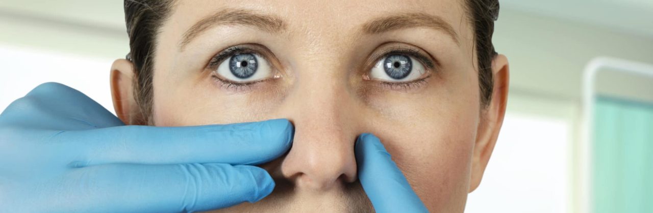 Doctor inspecting woman's nose